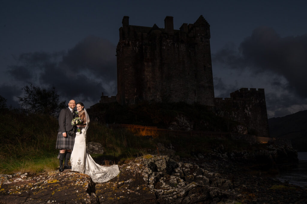 Bride and groom outside Eilean Donan Castle at night