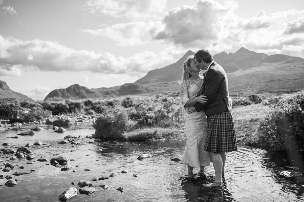black and white photo if a bride and groom standing in water on teh beach at an Affordable Elopement Skye