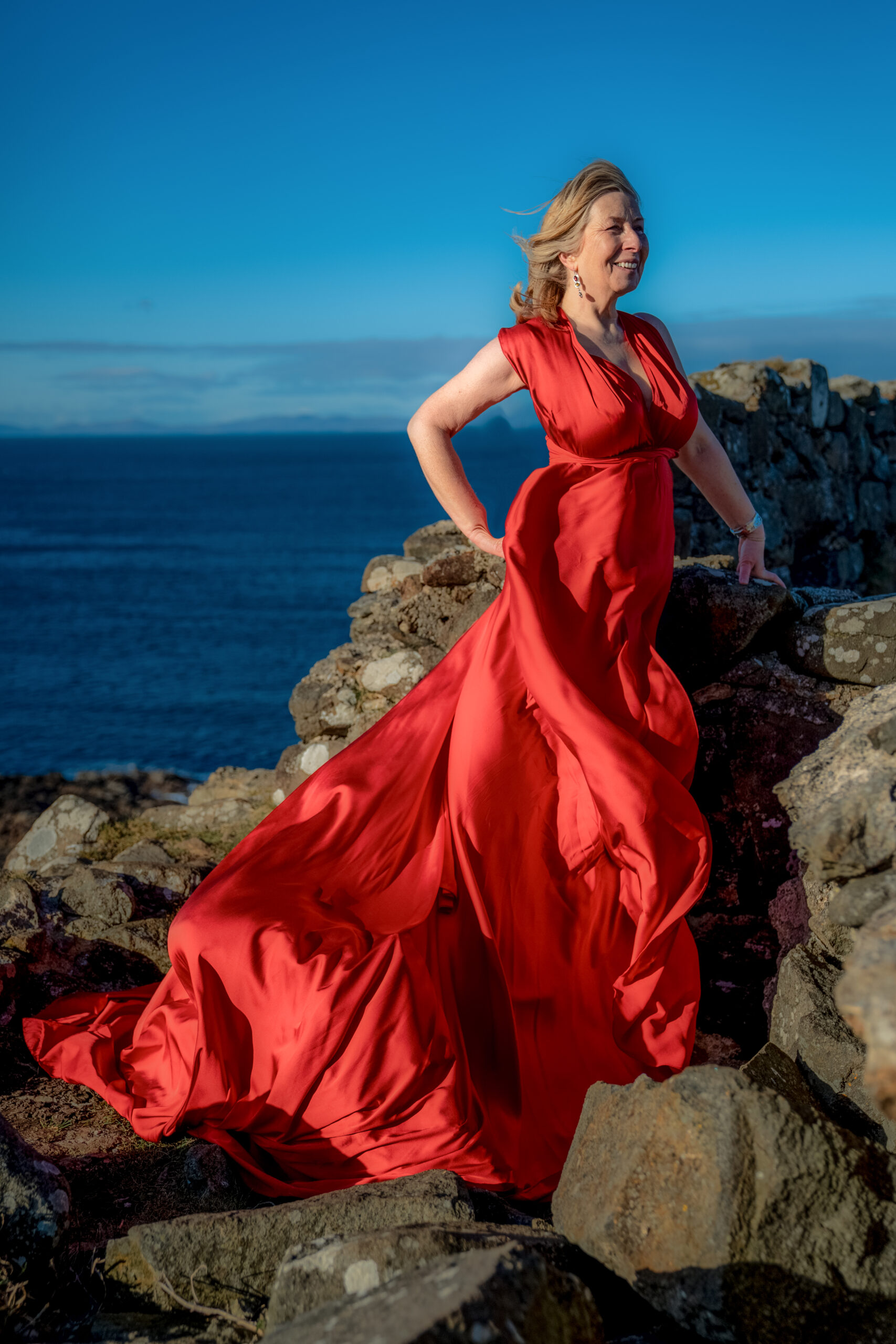 What to wear for a family photoshoot on the Isle of Skye woman in a long red dress on teh Isle of Skye