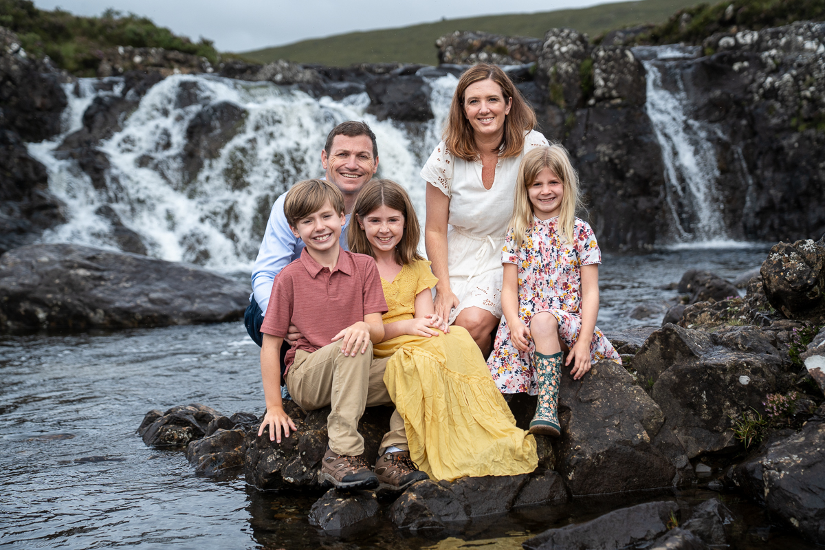 Family laughing together beside a Skye waterfall