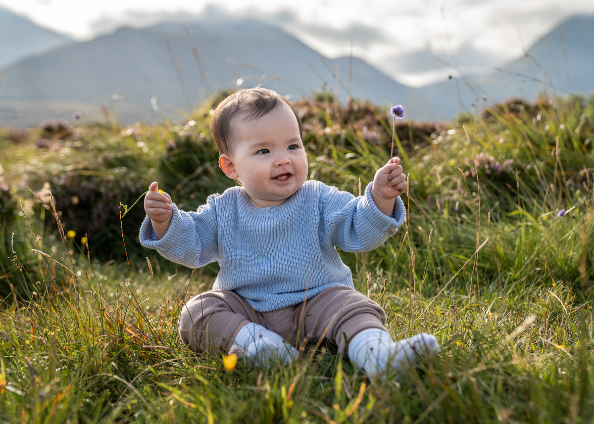 spring photoshoot on the Isle of Skye baby girl holds a flower in a spring photoshoot on the Isle of Skye