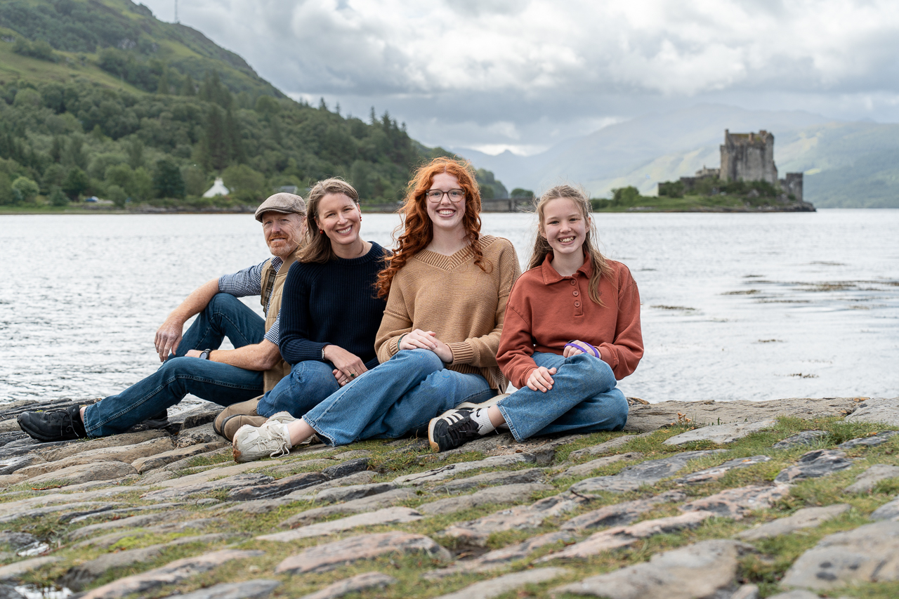 What to wear for a family photoshoot on the Isle of Skye family sitting by the sea in their family photoshoot